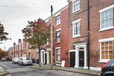 a red brick building with cars parked on a street at Avenham Apartments in Preston