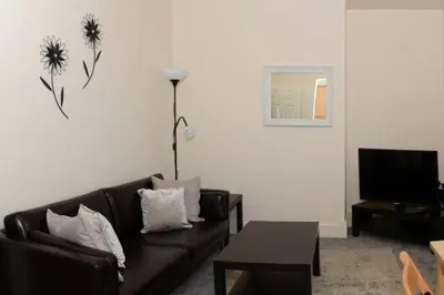 a living room with a black couch and a tv at Avenham Apartments in Preston