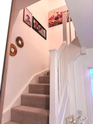 a stairway with white walls and white stairs with pictures at Room in Blackburn - Peters Place in Lower Darwen