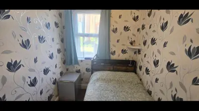 a bedroom with a bed with a floral wallpaper at Blackburn Rooms in Blackburn