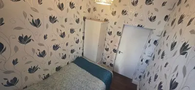 a small room with a bed and a wall with leaves at Blackburn Rooms in Blackburn