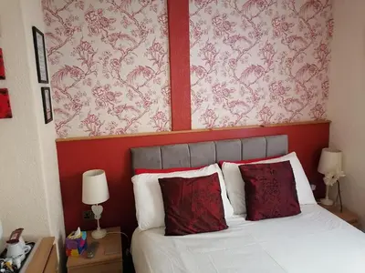 a bedroom with a bed with a red headboard and red wallpaper at The Manhattan in Blackpool