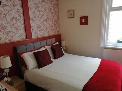a bedroom with a bed with red and white pillows at The Manhattan in Blackpool