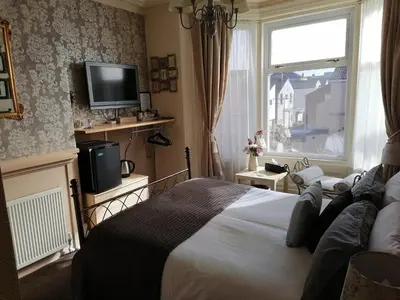 a bedroom with a bed and a tv and a window at The Manhattan in Blackpool