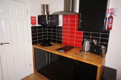 a kitchen with a counter and red tile on the wall at South Beach Apartments in Blackpool