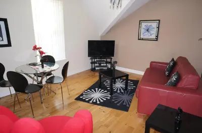 a living room with a red couch and a table at South Beach Apartments in Blackpool