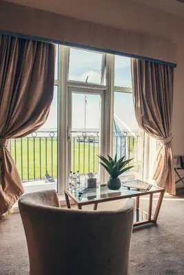 a living room with a table and a large window at Clifton Arms Hotel in Lytham St Annes