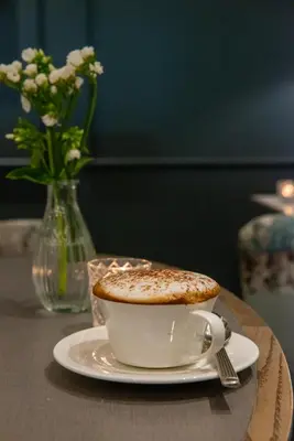 a cup of coffee on a table with a vase of flowers at Clifton Arms Hotel in Lytham St Annes
