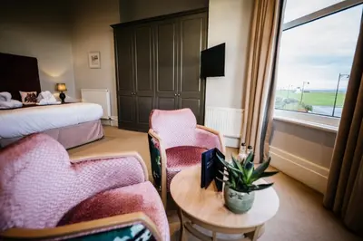 a hotel room with a bed and chairs and a table at Clifton Arms Hotel in Lytham St Annes