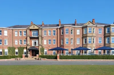 a large brick building with blue umbrellas in front of it at Clifton Arms Hotel in Lytham St Annes