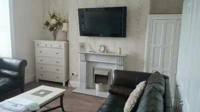 a living room with a black couch and a fireplace at Strathmore Apartments in Lytham St Annes