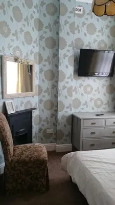 a bedroom with a bed and a tv and a chair at Strathmore Apartments in Lytham St Annes