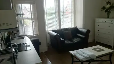 a living room with a leather chair and a table at Strathmore Apartments in Lytham St Annes