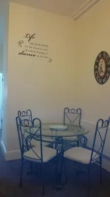 a table and two chairs and a table and a clock on the wall at Strathmore Apartments in Lytham St Annes