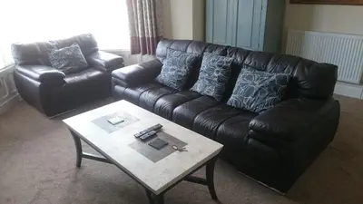 a living room with a leather couch and a coffee table at Strathmore Apartments in Lytham St Annes