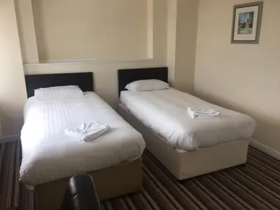 two beds in a hotel room with white sheets at Sunny Days Hotel in Blackpool