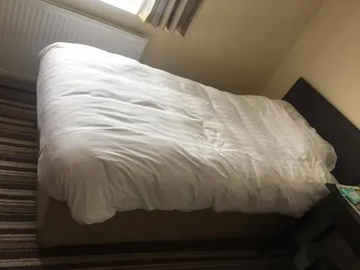 a bed with white sheets on it in a room at Sunny Days Hotel in Blackpool