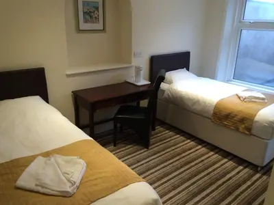 a room with two beds and a desk and a window at Sunny Days Hotel in Blackpool