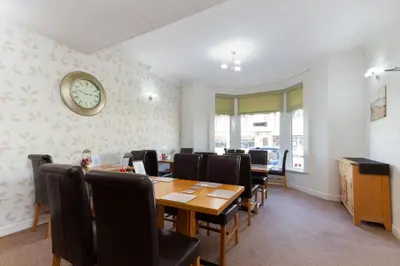 a dining room with a table and chairs and a clock at The Almeria in Blackpool