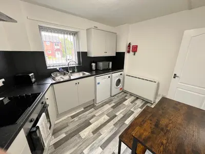 a kitchen with white cabinets and a wooden table at Marina Princes Reach in Preston