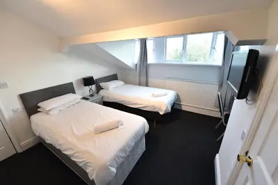 a small room with two beds and a television at Ashwood Hotel in Preston