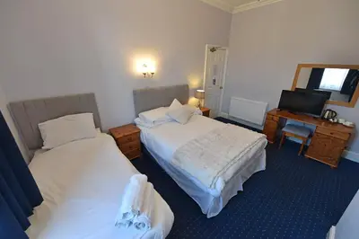 a hotel room with two beds and a desk at Ashwood Hotel in Preston