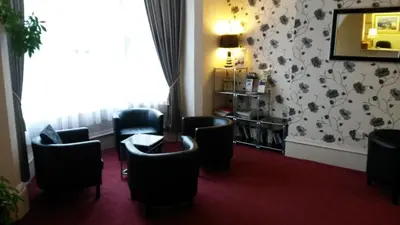 a waiting room with chairs and a table and a mirror at Ashwood Hotel in Preston