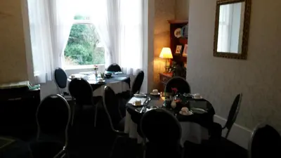 a dining room with tables and chairs and a window at Ashwood Hotel in Preston