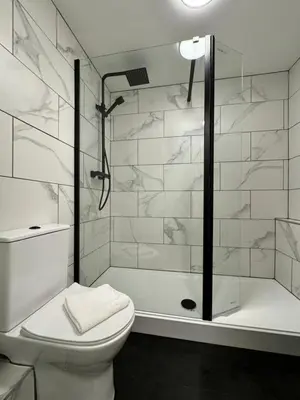 a white bathroom with a shower and a toilet at Nordic Suites Apartments, Ulverston in Ulverston