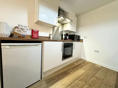 a kitchen with white cabinets and a wooden floor at Nordic Suites Apartments, Ulverston in Ulverston