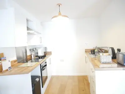 a kitchen with white cabinets and wooden counter tops at Nordic Suites Apartments, Ulverston in Ulverston