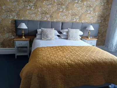 a bedroom with a large bed with a yellow blanket at Ormsgill Inn in Barrow in Furness