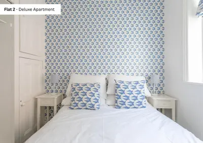 a bedroom with a bed with blue and white wallpaper at The Chymes Holiday Flats in Lytham St Annes