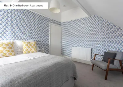 a bedroom with a bed and a chair at The Chymes Holiday Flats in Lytham St Annes