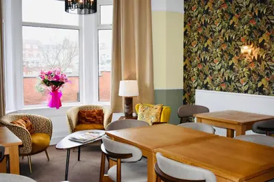 a waiting room with tables and chairs and a window at The Franklyn Hotel B&B in Blackpool