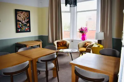 a waiting room with tables and chairs and a window at The Franklyn Hotel B&B in Blackpool