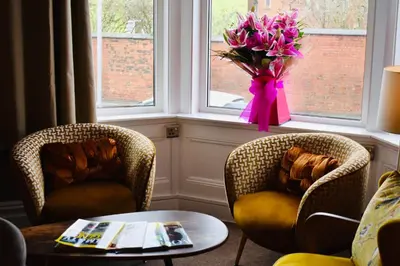 two chairs and a table with a vase of flowers in a window at The Franklyn Hotel B&B in Blackpool