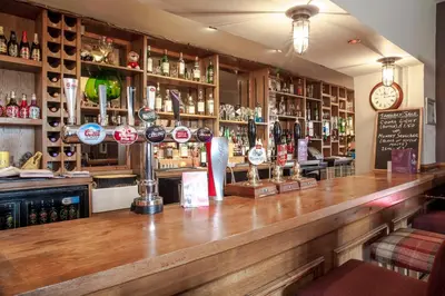 a bar with a wooden counter and a clock at Crofters Lodge in Barrow in Furness