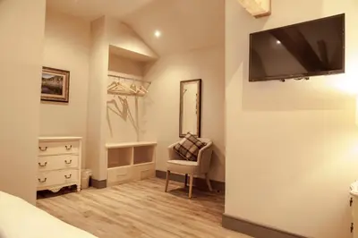 a bedroom with a tv on the wall and a chair at Crofters Lodge in Barrow in Furness