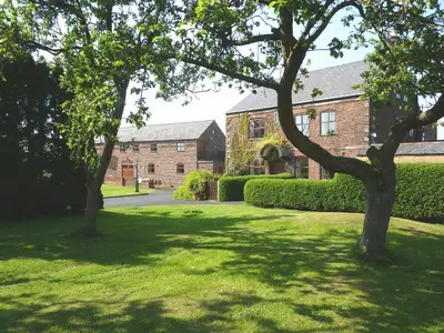 two trees in a lawn in front of a building at Parr Hall Farm, Eccleston in Eccleston