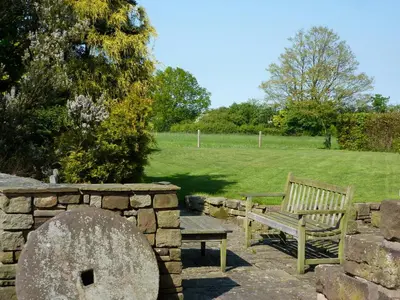 a park bench and a stone wall with a field at Parr Hall Farm, Eccleston in Eccleston