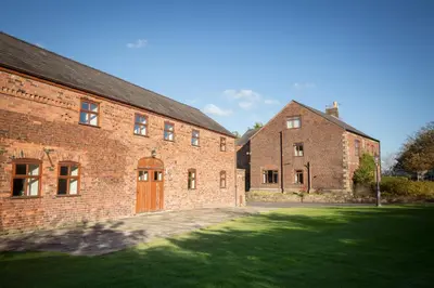 a large brick building with a door and a grass yard at Parr Hall Farm, Eccleston in Eccleston