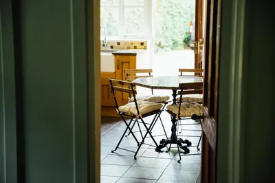 a table and chairs in a kitchen with a window at Langs Hall in Leyland