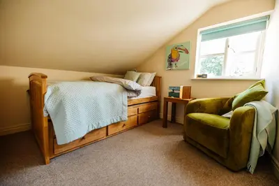 a bedroom with a bed and a chair and a window at Langs Hall in Leyland
