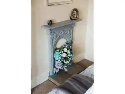 a fireplace with a bouquet of flowers on it at Langs Hall in Leyland