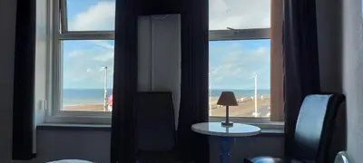 a room with two windows and a table with a lamp at Bowies Lodge in Blackpool