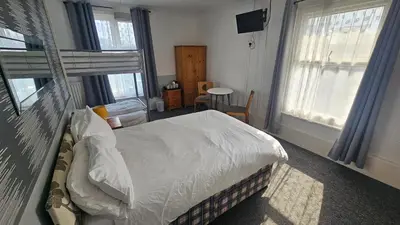 a bedroom with a bed and two windows at Bowies Lodge in Blackpool