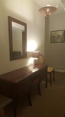 a room with a table and a mirror and a lamp at Maindee Guest House in Barrow in Furness