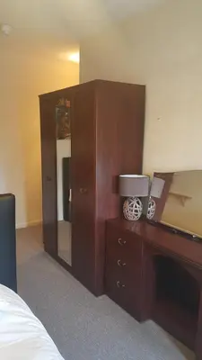 a bedroom with a bed and a dresser and a mirror at Maindee Guest House in Barrow in Furness