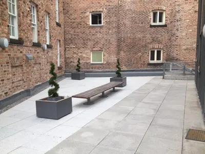 a courtyard with a bench and potted trees in front of a building at Campbell Square Apartment 3 in Liverpool